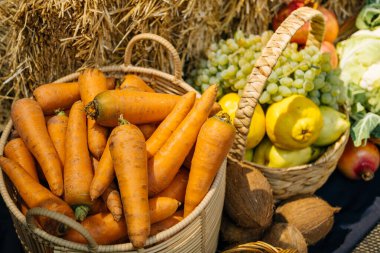 Samanla çevrili taze toplanmış havuç, üzüm ve olgun armutlardan oluşan canlı bir gösteri.