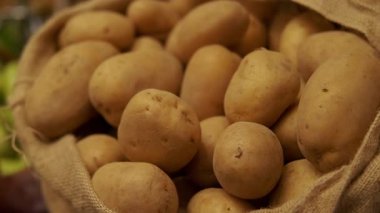 Taze ve lezzetli patateslerin büyüleyici ve organik cazibesini tara. Kırsal bir çuvala güzelce doldurulmuş.
