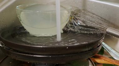 Su temiz bir kase ve parlak bir çırpı üzerinde akar, mutfaktaki mutfak aktivitelerinin özünü yakalar.