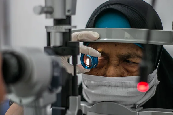 BOGOR, INDONESIA - 27 Mart 2023: Endonezya 'nın Bogor Regency Bölgesi, Ainun Cahaya Medika göz kliniğinde bir özel mikroskop kullanan bir vatandaş, 27 Mart 2023 tarihinde bir göz testi gerçekleştirdi.
