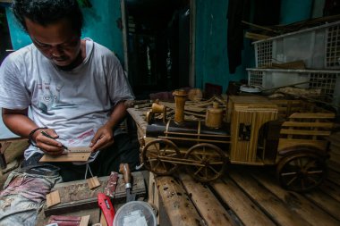 BOGOR, INDONESIA - 17 Haziran 2023: Bogor, Batı Java, Endonezya 'da bir zanaatkar bambudan otomotiv minyatürleri yapıyor, 17 Haziran 2023. Bambudan yapılan otomotiv çevre dostu ve güzel bir üründür.