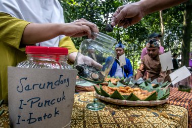 Bogor City, Endonezya - 23 Temmuz 2023 - Alıcılar bir köy çerez festivalinde para yerine bir kabuk değerinde hindistan cevizi kabuğu kırıntılı abur cuburlar için ödeme yapıyorlar.
