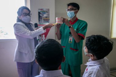 Bogor, Endonezya - 31 Temmuz 2023: Diş hekimleri, Endonezya 'daki Vania Bogor Hastanesi' ni ziyaret eden ilkokul öğrencilerine diş sağlığı ve diş sağlığının korunması konusunda eğitim sunuyor