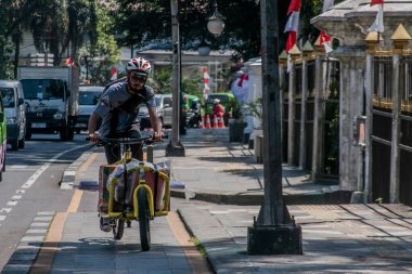 Bir bisikletli kurye, 1 Ağustos 2023 'te müşterinin Bogor, West Java, Endonezya' daki adresine mal teslimatı yapar.