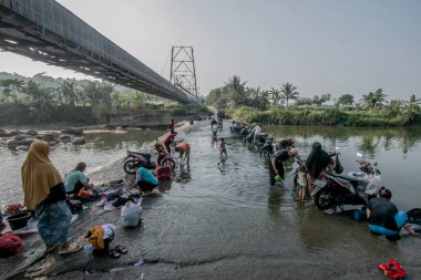 Bogor, Endonezya - 05 Ağustos 2023: Gunung Sari Köyü, Bogor Regency, West Java, Endonezya sakinlerinin faaliyetleri, Lulud Nehri 'nde çamaşır ve motosikletleri yıkamak, çünkü evlerindeki su kurak mevsim nedeniyle kurumuş.