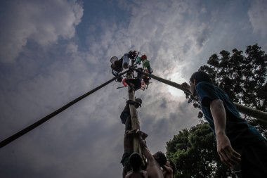 Bogor, Endonezya - 17 Ağustos 2023: Çocuklar 17 Ağustos 2023 'te Bogor, Batı Java, Endonezya' da düzenlenen 78. Bağımsızlık Günü kutlamalarında kayganlaştırıcı kaplı bir ağaç gövdesine tırmanarak asılma ödüllerini toplamak için yarışıyorlar.