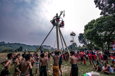 Bogor, Endonezya - 17 Ağustos 2023: Çocuklar 17 Ağustos 2023 'te Bogor, Batı Java, Endonezya' da düzenlenen 78. Bağımsızlık Günü kutlamalarında kayganlaştırıcı kaplı bir ağaç gövdesine tırmanarak asılma ödüllerini toplamak için yarışıyorlar.