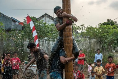 Bogor, Endonezya - 20 Ağustos 2023: Indonezya 'nın 78. Bağımsızlık Günü' nde Bogor, Batı Java 'da asılı kalan ürünler için bagajı yağlayıcı sıvıyla kaplanmış bir betel fıstığına tırmanmak için yarışan vatandaşlar