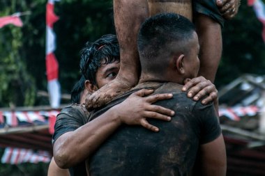 Bogor, Endonezya - 20 Ağustos 2023: Indonezya 'nın 78. Bağımsızlık Günü' nde Bogor, Batı Java 'da asılı kalan ürünler için bagajı yağlayıcı sıvıyla kaplanmış bir betel fıstığına tırmanmak için yarışan vatandaşlar