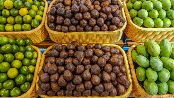 Süpermarketteki meyve raflarında taze mango, yılan meyvesi ve portakal koleksiyonu.