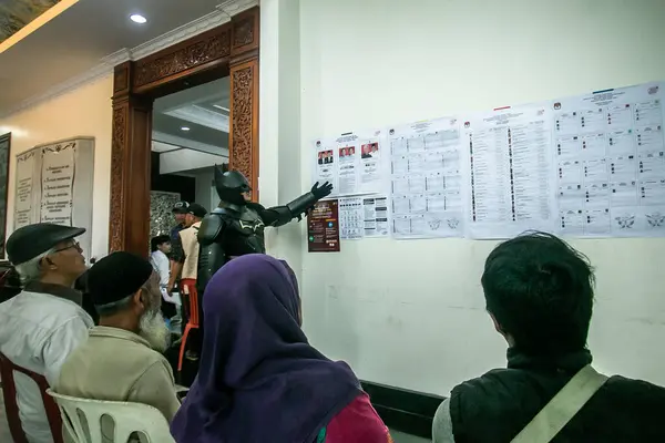 Batman süper kahraman kostümü giyen bir seçim yetkilisi Endonezya 'da 14 Şubat 2024' te Bogor, Endonezya 'daki bir sandık merkezinde başkanlık ve yasama seçimlerinde çalışıyor..