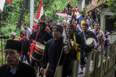Bogor, Endonezya - 7 Temmuz 2024: Sidekah Bumi 'yi kutlamak için yapılan geçit töreninde vatandaşlar toplumla paylaşmak üzere tarım, tarım ve çiftlik ürünleri getirerek Sundan müziği çalıyorlar.