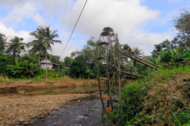 Sukabumi, Endonezya - 24 Temmuz 2024: Bir vatandaş Sukabumi, Batı Java 'daki Cikaso Nehri üzerinde pirinç tarlalarını sulamak için bir bambu su çarkı inşa eder..