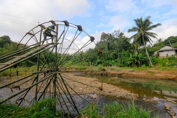Sukabumi, Endonezya - 24 Temmuz 2024: Bir vatandaş Sukabumi, Batı Java 'daki Cikaso Nehri üzerinde pirinç tarlalarını sulamak için bir bambu su çarkı inşa eder..