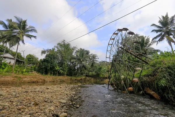 Sukabumi, Endonezya - 24 Temmuz 2024: Bir vatandaş Sukabumi, Batı Java 'daki Cikaso Nehri üzerinde pirinç tarlalarını sulamak için bir bambu su çarkı inşa eder..