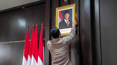 A police officer installs a photo figura of Indonesian President Prabowo Subianto on the wall of a room on October 21, 2024 in Bogor City. Prabowo becomes the eighth president of Indonesia for the 2024-2029 term clipart