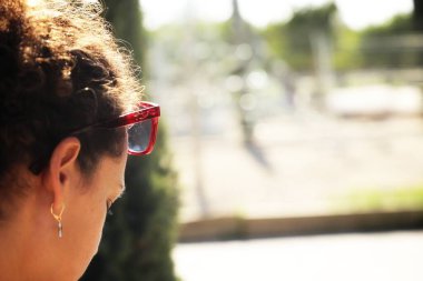 Siyah güneş gözlüklü, beyaz gömlekli, arka planda bıyıklı genç bir adam..