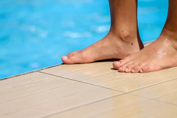 feet of the young man in blue swimming suit on a swimming mat