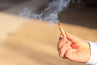 Sokakta yanan sigarayla el ele tutuşan kadın.