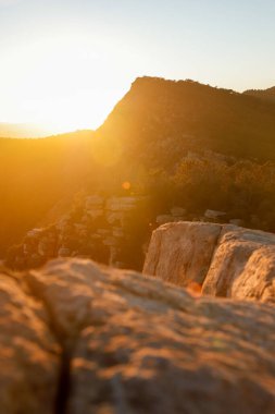Güneş bulutların arasından bir dağ manzarasında ışıldıyor.