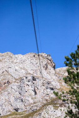 Arka planda teleferik olan yüksek dağ zirvesi