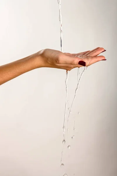 hands of a young woman dripping clear water, white background