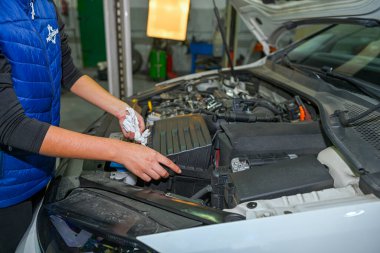 Genç bayan tamirci, bir araba motorunun tamiri üzerinde çalışıyor.