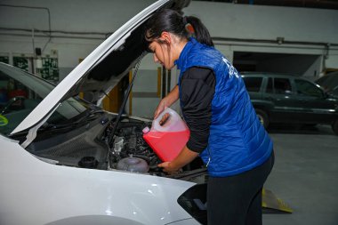 Genç bayan tamirci, bir araba motorunun tamiri üzerinde çalışıyor.