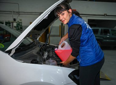 Genç bayan tamirci, bir araba motorunun tamiri üzerinde çalışıyor.
