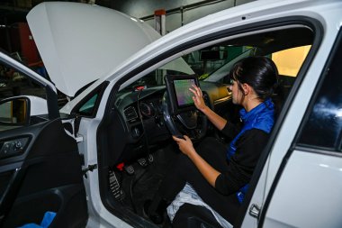 Genç bayan tamirci, bir araba motorunun tamiri üzerinde çalışıyor.