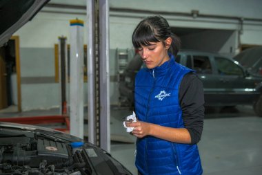 Genç bayan tamirci, bir araba motorunun tamiri üzerinde çalışıyor.