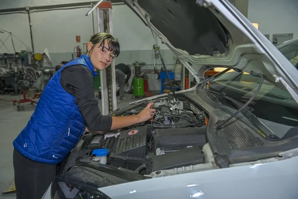 Genç bayan tamirci, bir araba motorunun tamiri üzerinde çalışıyor.