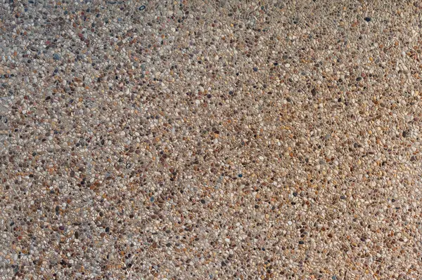 Close-up of a concrete surface embedded with a multitude of smooth, multicolored pebbles.