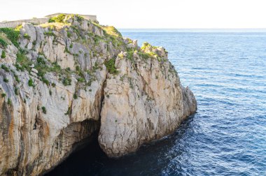 Doğal bir kireçtaşı uçurumu berrak gökyüzünün altındaki sakin mavi deniz sularının üzerinde görkemli kuleler.