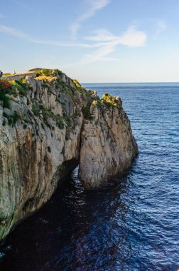 Doğal bir kireçtaşı uçurumu berrak gökyüzünün altındaki sakin mavi deniz sularının üzerinde görkemli kuleler.