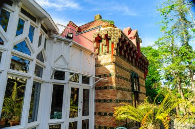 Comillas, Cantabria, İspanya 'nın bereketli manzarasında gündüz vakti aya karşı kurulmuş görkemli tarihi bir konak.