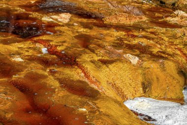 Close-up of iron sulfate formations creating a mosaic of reds and oranges in the Rio Tinto's waters