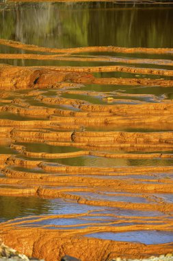 Sunset illuminates the terraced mineral pools, showcasing the vibrant geological layers at Rio Tinto