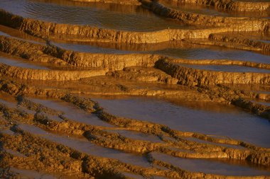 Sunset illuminates the terraced mineral pools, showcasing the vibrant geological layers at Rio Tinto