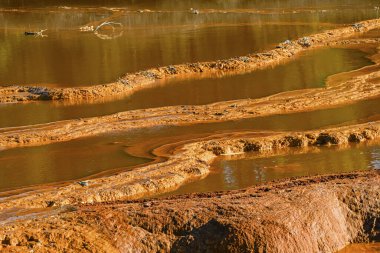 Sunset illuminates the terraced mineral pools, showcasing the vibrant geological layers at Rio Tinto