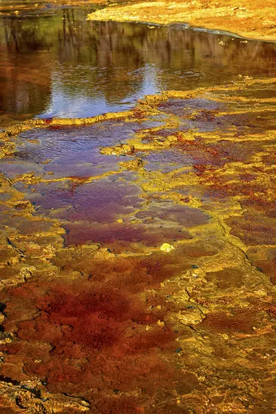 stock image Close-up of iron sulfate formations creating a mosaic of reds and oranges in the Rio Tinto's waters