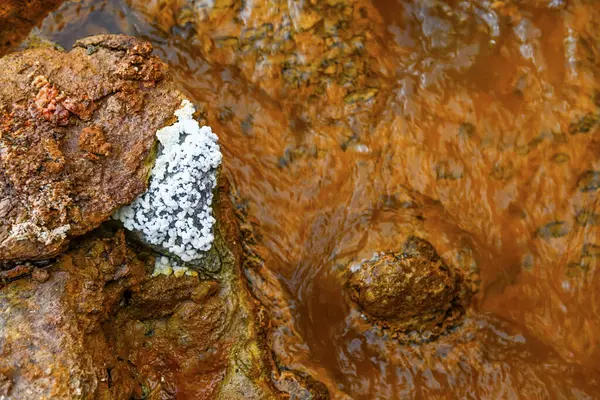 Crystal formations juxtaposed with the orange, iron-infused waters of Rio Tinto, displaying a stark natural contrast