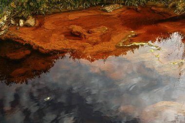 The Rio Tinto in Huelva, Spain, exhibits striking red and orange iron-rich deposits and green microorganism traces