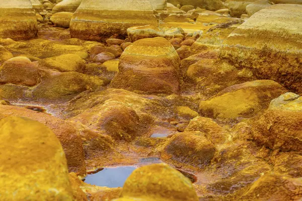 The warm, orange mineral deposits of Rio Tinto sculpt a textured landscape with reflective puddles