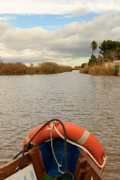 Albufera Valencia 'nın sakin sularında süzülen bir tekneden görüntü, sazlıklar ve bulutlarla kaplı gökyüzü