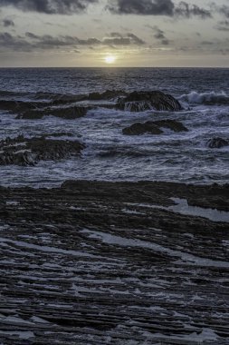 Carriagem Sahili, Portekiz 'de dramatik bulut oluşumlarıyla kasvetli bir gökyüzü. Engebeli kıyı şeridi ve kaya oluşumları alacakaranlıkta çarpıcı ve atmosferik bir manzara yaratır..