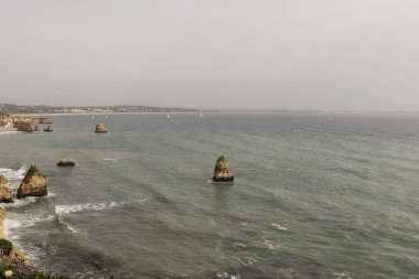 Portekiz 'deki Camilo Sahili' ndeki kayalık kayalıkların ve deniz yığınlarının manzarası. Engebeli kıyı şeridi dramatik kaya oluşumları ve kumlu bir plaja sahiptir..