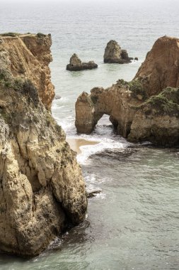 Portekiz 'deki Camilo Sahili' ndeki kayalık kayalıkların ve deniz yığınlarının manzarası. Engebeli kıyı şeridi dramatik kaya oluşumları ve kumlu bir plaja sahiptir..