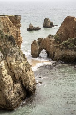 Portekiz 'deki Camilo Sahili' ndeki kayalık kayalıkların ve deniz yığınlarının manzarası. Engebeli kıyı şeridi dramatik kaya oluşumları ve kumlu bir plaja sahiptir..