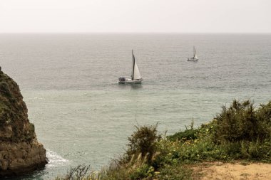 Portekiz 'deki Camilo Sahili' ndeki kayalık kayalıkların ve deniz yığınlarının manzarası. Engebeli kıyı şeridi dramatik kaya oluşumları ve kumlu bir plaja sahiptir..